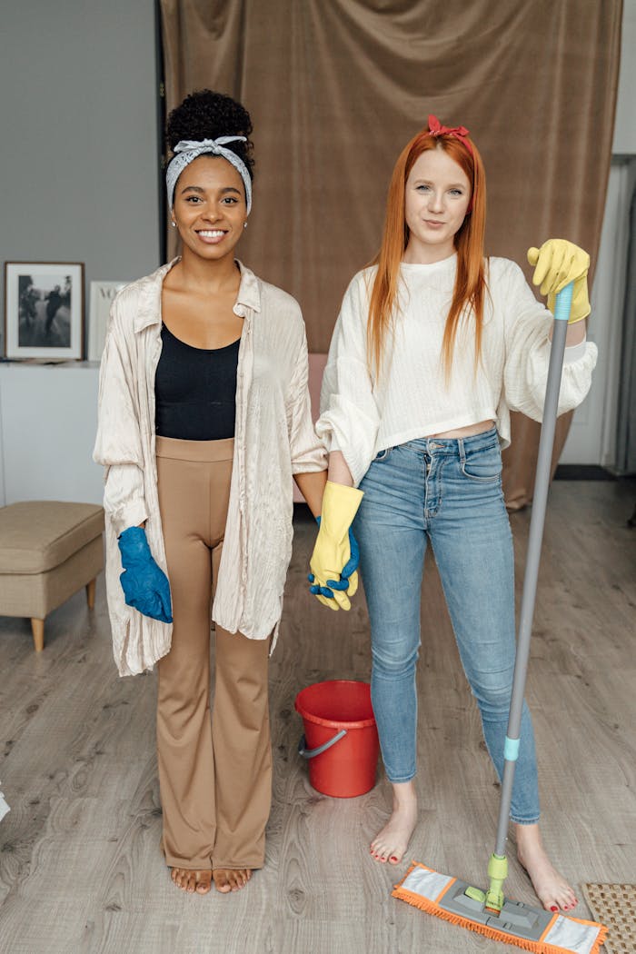 home-hero-bg Two women smiling and holding hands while cleaning indoors, symbolizing teamwork.